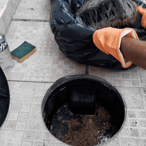 Caixa de gordura saturada sendo limpa por equipe profissional em restaurante de São Paulo